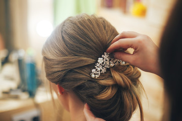 Hairdresser makes hairstyle for a young girl. Close up