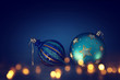 Image of christmas festive tree ball decoration with gold stars in front of blue background.