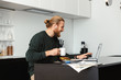 © Drobot Dean - Handsome young bearded man sitting at the kitchen drinking coffee using laptop computer.