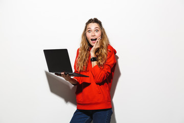 Sticker - Image of adorable woman 20s wearing red sweatshirt holding laptop, isolated over white background