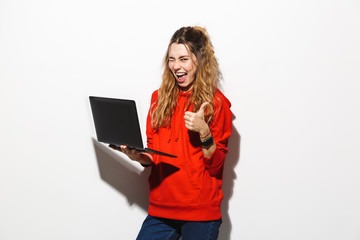 Sticker - Image of optimistic woman 20s wearing red sweatshirt holding laptop, isolated over white background