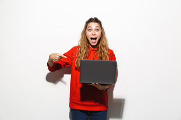 Sticker - Image of excited woman 20s wearing red sweatshirt holding laptop, isolated over white background