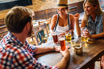 Wall Mural - Young cheerful people in the beer pub drinking and having good time