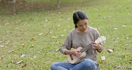 Wall Mural - Woman play ukulele in the park