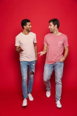 Canvas Print - Two cheerful men friends standing isolated over red