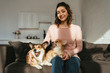 © LIGHTFIELD STUDIOS - attractive woman sitting on sofa with welsh corgi dogs at home