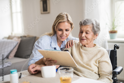 Fotografía A health visitor measuring a blood pressure of a senior woman at home