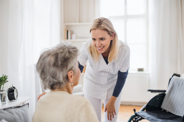 Wall Mural - A health visitor talking to a senior woman sitting on bed at home.