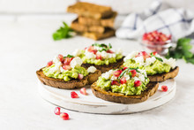 Avocado Feta Pomegranate Toasts On Cutting Board. Selective Focus, Space For Text.