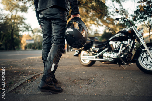 Fotografía Motorcyclist with helmet in hand goes to chopper