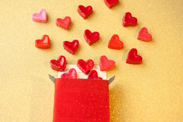 Wall Mural - Valentine's day concept. gift for Valentine's Day, a red box with sweet hearts on a gold background. Pictures of Love. selective focus