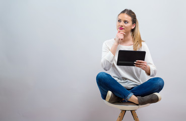 Wall Mural - Young woman with a tablet computer on a gray background