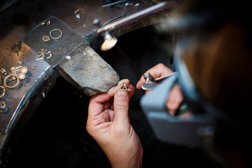 jeweler saws at a gold ring in authentic jewellery workshop