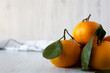 © Liudmyla - Fresh ripe unpeeled tangerines over white wooden background, side view. Copy space.