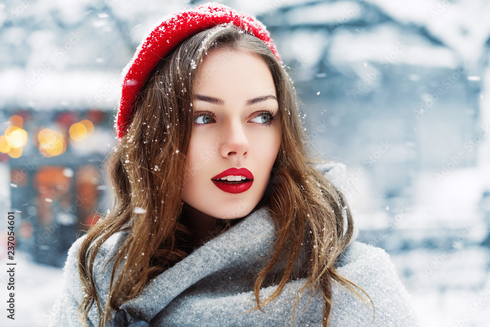 Outdoor close up portrait of young beautiful fashionable woman with red lips,  wearing woolen beret, scarf, posing in street of european city. Winter fashion, Christmas holidays concept. Copy space - obrazy, fototapety, plakaty 