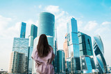 Fototapeta Miasta - girl in a pink cloak on the background of the Moscow International business center