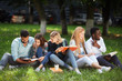 © alfa27 - Outdoor portrait of group of young mixed-race diverse students sitting together on green lawn reading their notes about their life at university campus
