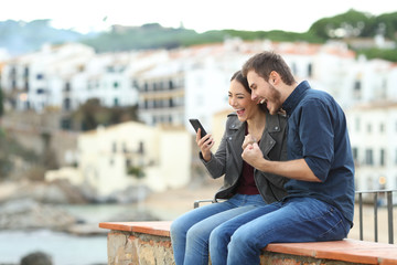 Sticker - Excited couple finding news on phone on a ledge