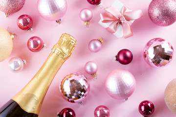 Wall Mural - Christmas party with champagne bottle and gift box on pink background