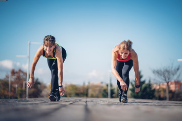 Wall Mural - Two beautiful women perform outdoor exercise in park.