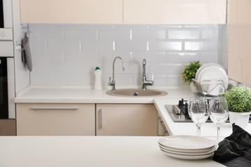 Wall Mural - Stack of clean dishes and glasses on table in kitchen. Space for text