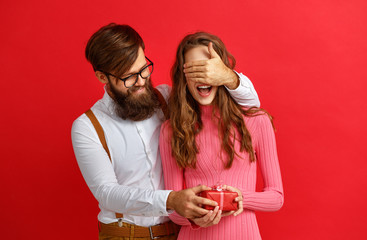 Wall Mural - valentine's day concept. happy young couple with heart, flowers, gift on red