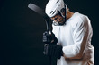 © alfa27 - Caucasian American hockey player, in white uniform and helmet, isolated on black, prays for good luck, wishes triumph and victory.