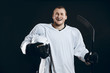 © alfa27 - Happy Handsome hockey player with one broken front tooth laughing at camera, standing with stick in white uniform, isolated on black