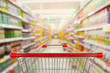 © Kwangmoozaa - Supermarket aisle interior blur background with empty red shopping cart