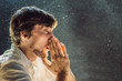 © galitskaya - Allergy to dust. A man sneezes because he is allergic to dust. Dust flies in the air backlit by light