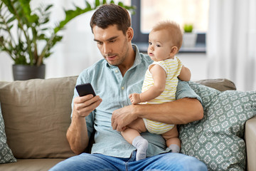 Poster - family, fatherhood and technology concept - father with little baby daughter using smartphone at home