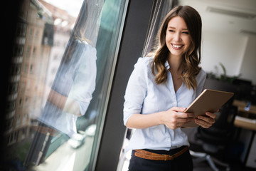 attractive businesswoman using a digital tablet while standing in front of windows