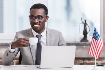 Wall Mural - African american businessman holding cup with drink in modern office