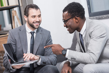 Wall Mural - african american businessman pointing with finger at business partners laptop in office