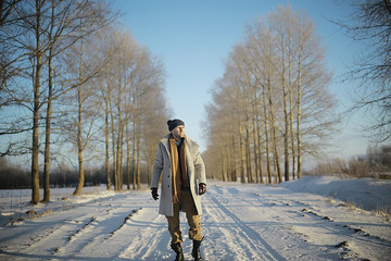 Wall Mural - fashionable man in a coat / winter style, walk against the backdrop of the winter landscape, snowy weather, warm clothes