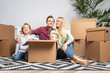 © snedorez - Photo of young parents and children among cardboard boxes sitting on floor in new apartment
