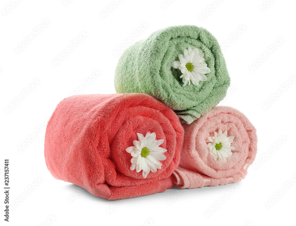 Rolled clean soft towels with flowers on white background