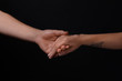 © Pixel-Shot - Man and woman holding hands on dark background