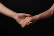 © Pixel-Shot - Man and woman holding hands on dark background