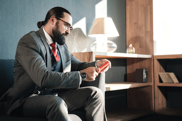 Serious bearded businessman reading e-mails on his red phone