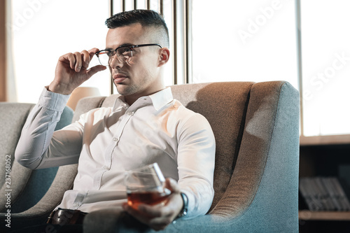 Fotografie, Tablou Young dark-haired businessman feeling rested while drinking whisky