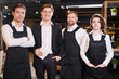 © Seventyfour - Team of restaurant professionals in ahead of manager standing in line and smiling at camera