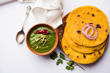 Makki di roti with sarson ka saag, popular punjabi main course recipe in winters made using corn breads mustard leaves curry. served over moody background. selective focus