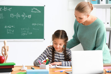 Poster - Cute girl with teacher doing homework in classroom