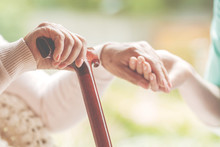 Closeup Of Senior Lady Holding Walking Stick In One Hand And Holding Nurse's Hand In The Other