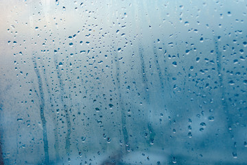 Strong humidity in wintertime. Water drops from home condensation on a window. Misted glass background