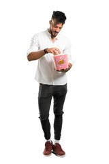 A full-length shot of a Arabic young man with white shirt eating popcorns in a big bowl on isolated white background