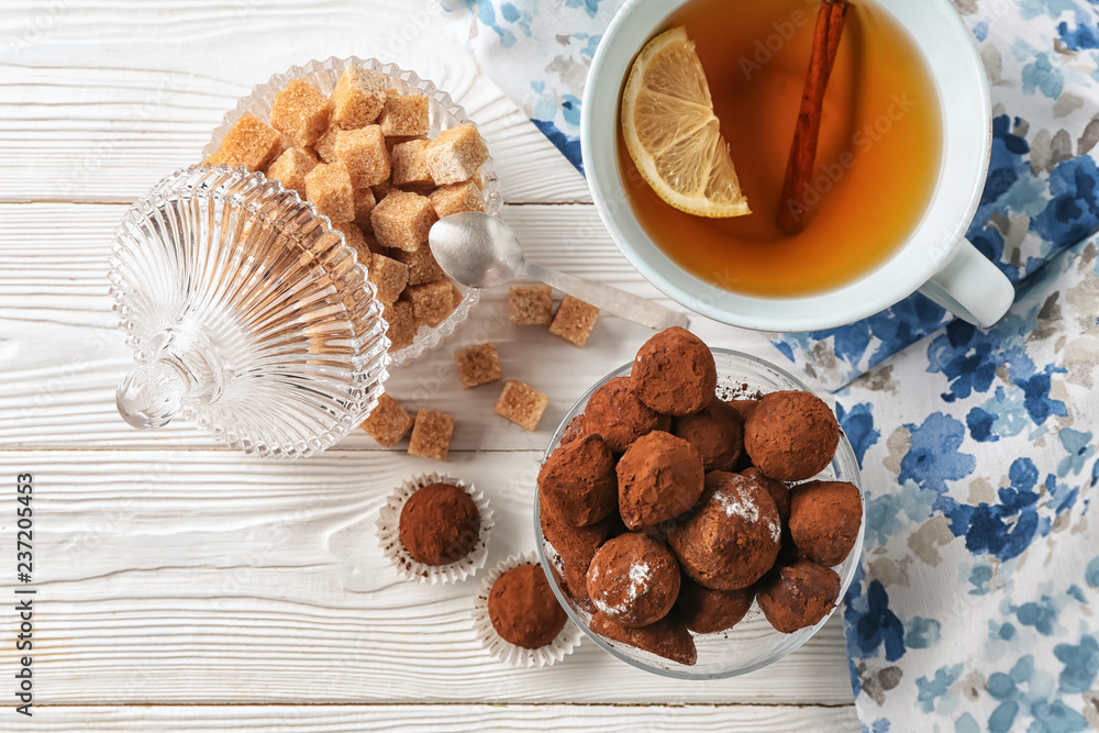 Cup of tea with chocolate truffles on light table