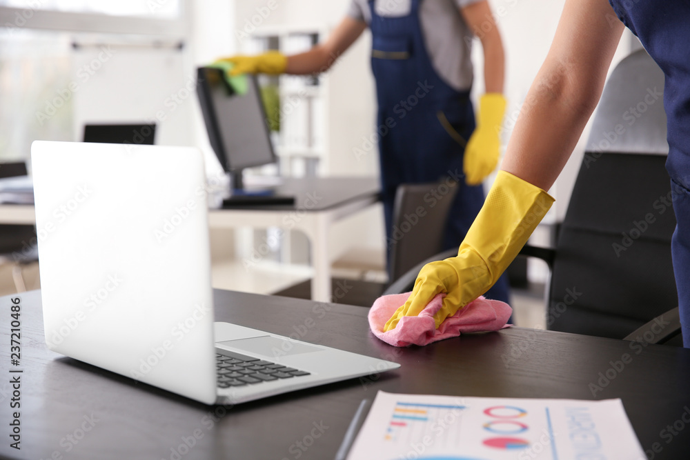 Janitor wiping table in office - obrazy, fototapety, plakaty 