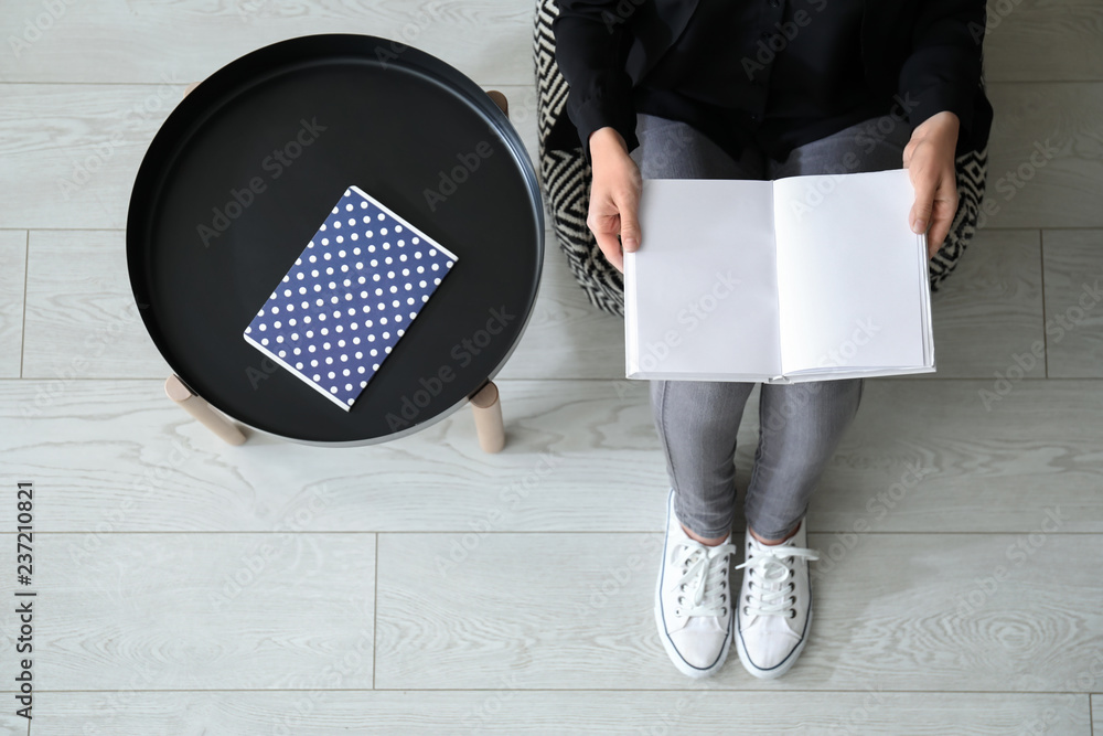 Young woman reading book at home, top view